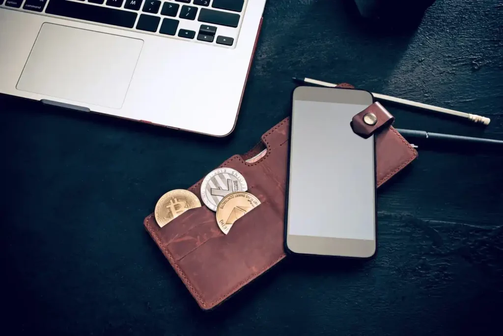 Workstation with a leather wallet containing cryptocurrency coins and a smartphone