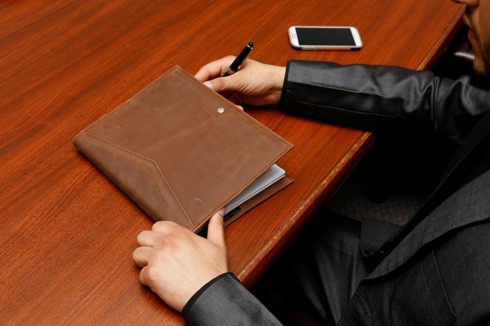 A person with a pen in his hand to sign document