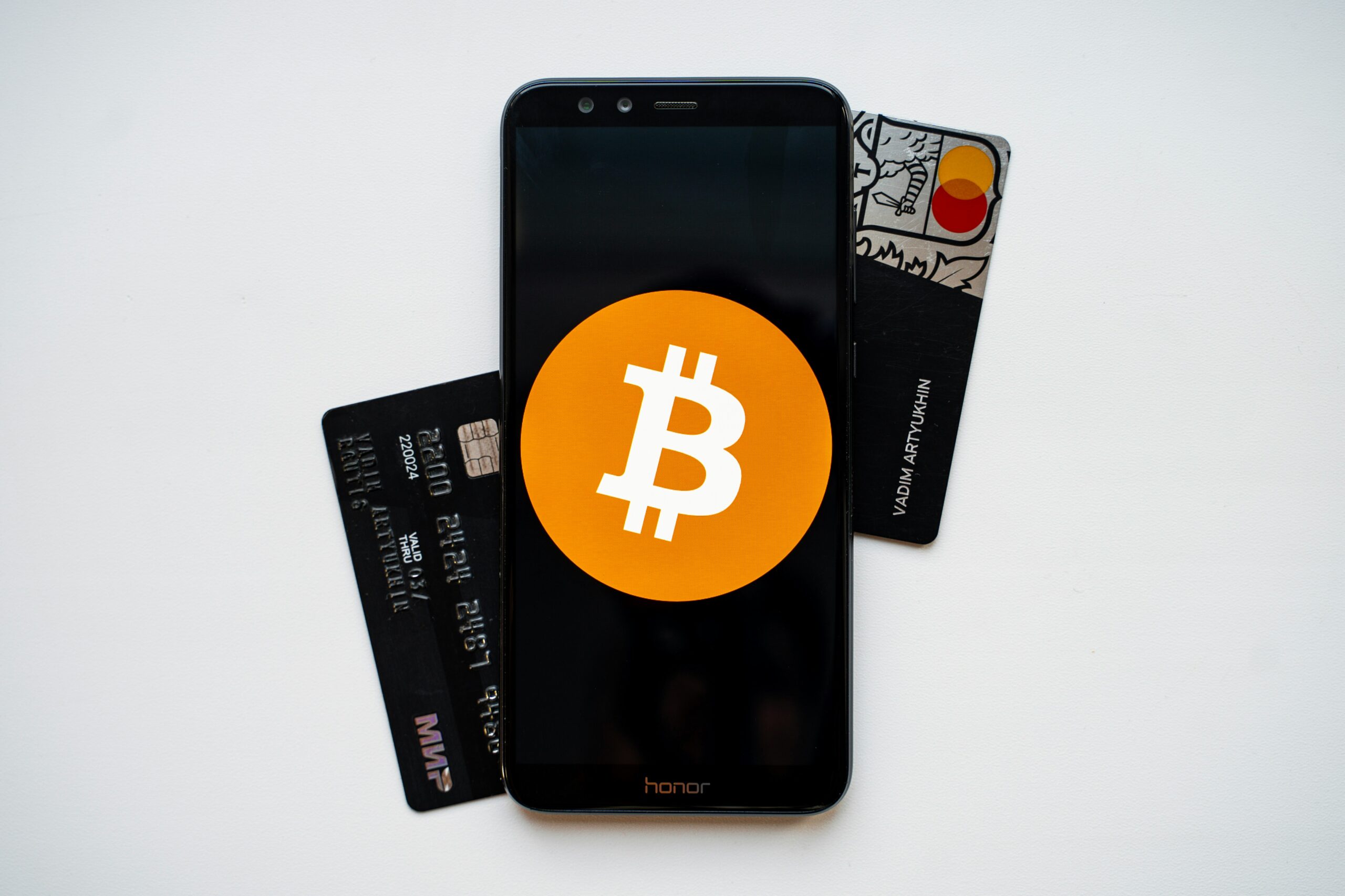 Two crypto credit cards and a smartphone with the Bitcoin symbol on the screen