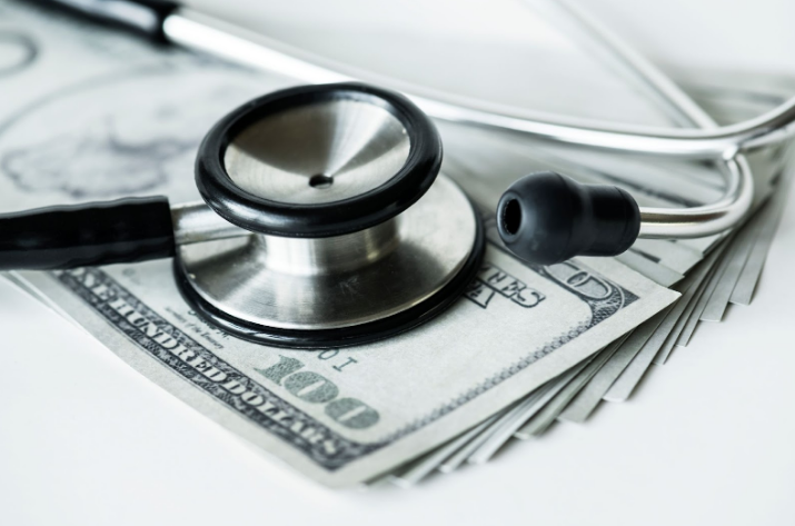 Closeup of a stethoscope on a stack of hundred-dollar bills