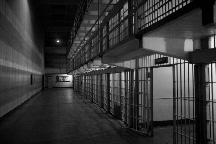 Dimly lit corridor of a prison with cell doors open