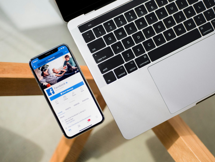 A smartphone with the Facebook app open, next to a laptop