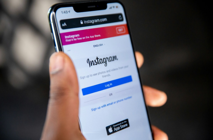 Hand holding a smartphone displaying Instagram login page, sign-in options clearly visible