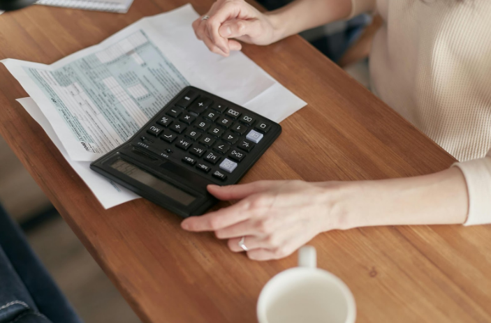 A woman in paperwork with a calculator on a table