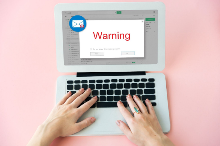 Laptop showing a “Warning” popup in an email inbox, relevant for Google Chat security awareness