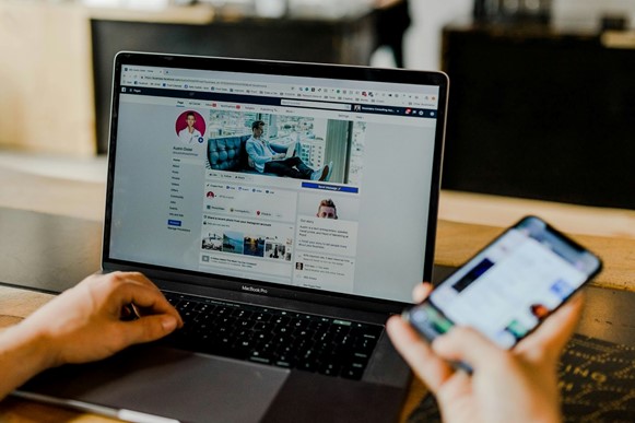 Person browsing Facebook on a laptop and smartphone