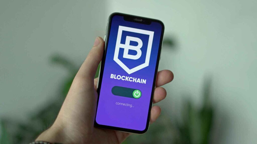 Hand holding a smartphone displaying a blockchain app with a connecting status