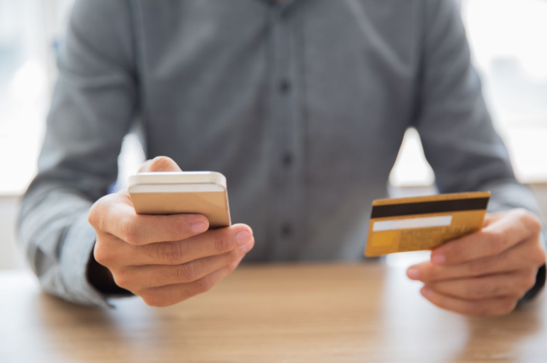 Person holding a mobile phone in one hand and a credit card in the other, ready to make a payment