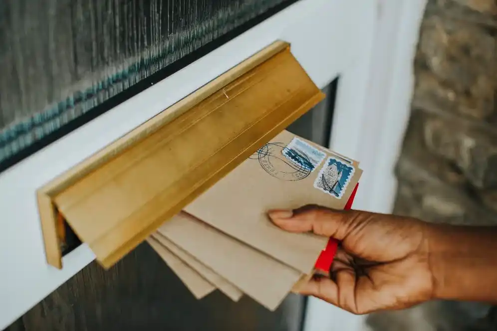 Person retrieving letters from a mailbox, emphasizing the importance of secure mail practices