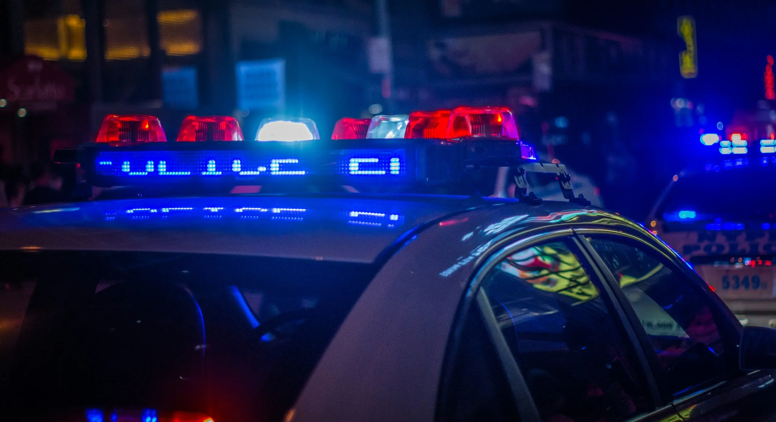 Police cruiser with flashing red and blue lights at night, representing law-enforcement response to theft and fraud